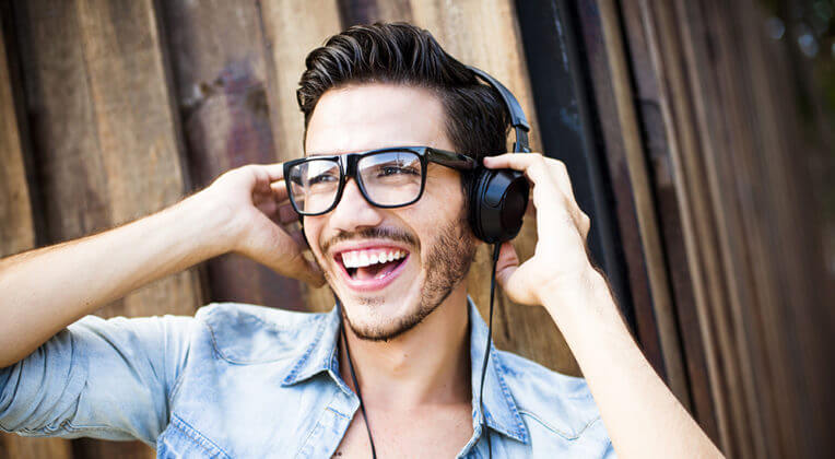 Seorang pria tersenyum dengan on-ear headphone di telinganya